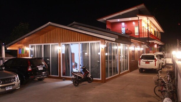 Ein Gebäude mit überdachter Eingangspartie, einer Garage mit geparkten Fahrzeugen und einem Fahrradständer.