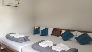 Ein Doppelbett mit grau-weißer Bettwäsche, türkisfarbenen Kissen und gefalteten Handtüchern.