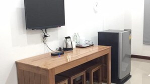 Eine kleine Küchenzeile mit einem Holztisch, einem an der Wand montierten Fernseher und einem Kühlschrank.