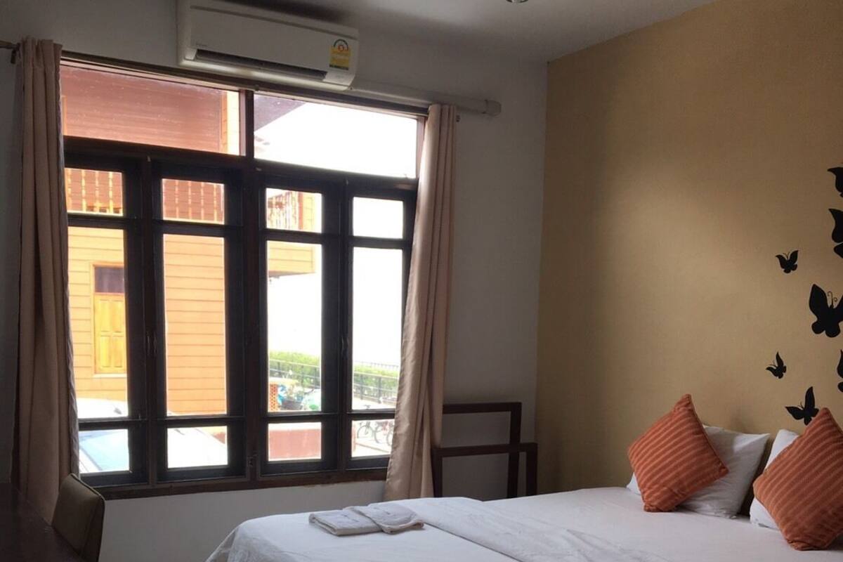 A hotel room with a bed, a desk, and a window with curtains.