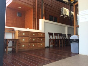 A wooden interior with a large wooden cabinet, a bench, and a trash bin. - Norn Nab Dao Rimkhong (Chiang Khan)
