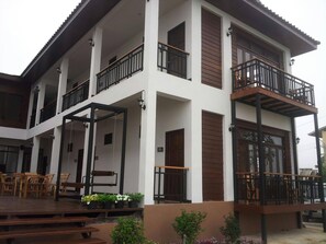 A multi-story building with balconies, wooden deck, and potted plants. - Norn Nab Dao Rimkhong (Chiang Khan)