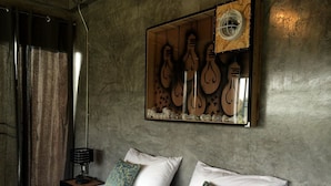 Un dormitorio con cama, almohadas, mesita de noche, lámpara y luz empotrada en la pared.