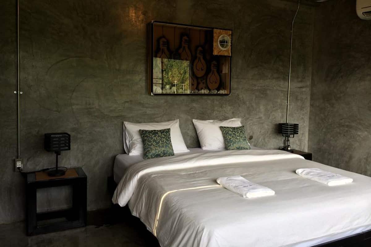 Un dormitorio con una cama grande, dos mesitas de noche y una obra de arte colgada en la pared.