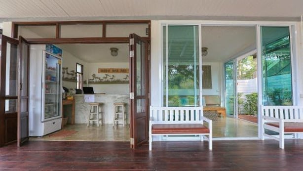 Una habitación amplia con piso de madera, un banco y una puerta de vidrio que da a un espacio exterior.