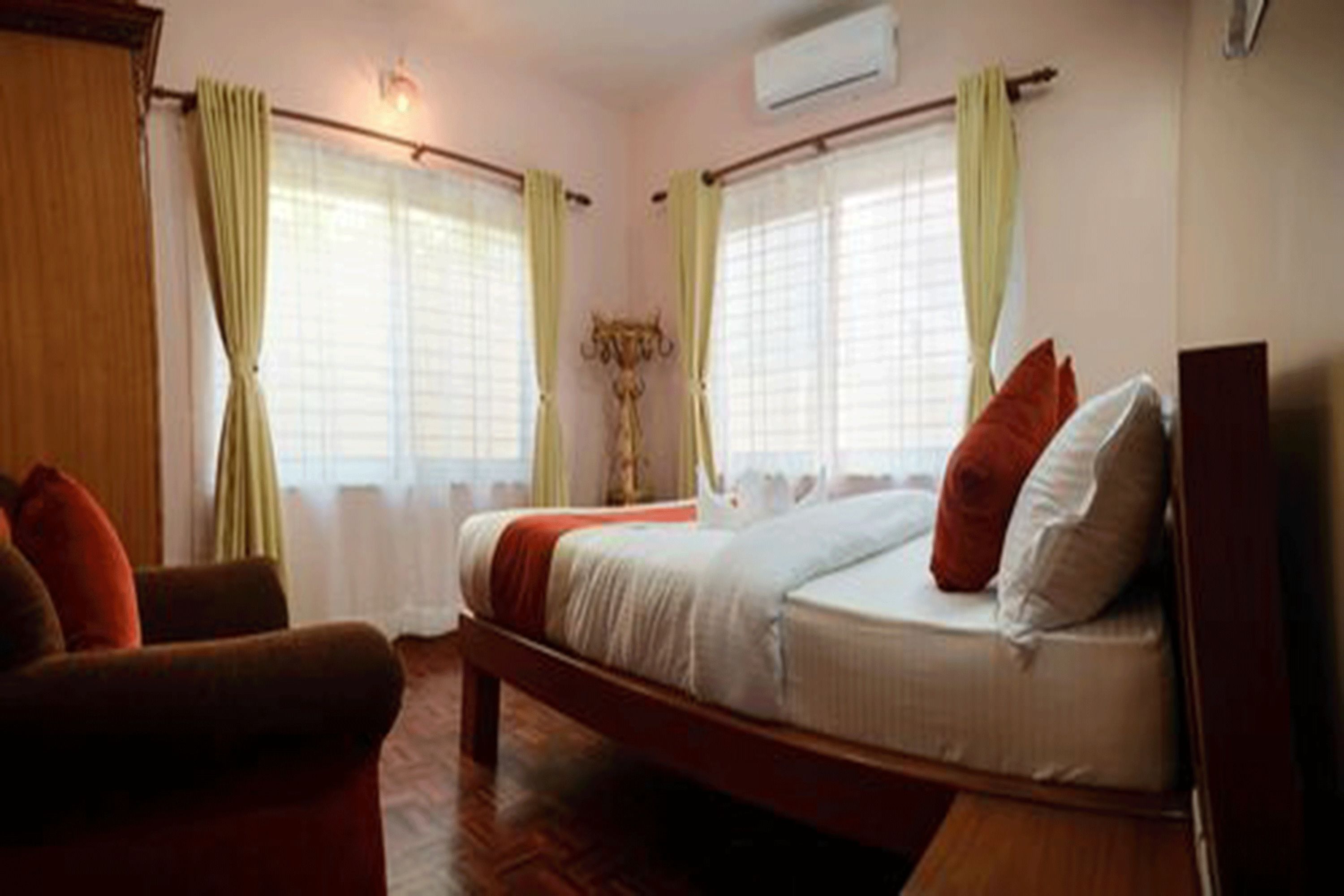 A bedroom with a bed, a chair, and a window with curtains.
