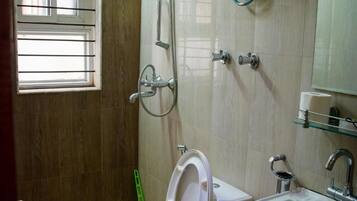 A bathroom with a toilet, sink, shower, and a window with bars.