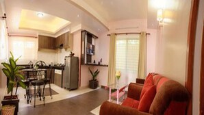 Una sala de estar moderna con sofá, un comedor con sillas, una zona de cocina y un ventanal con cortinas.