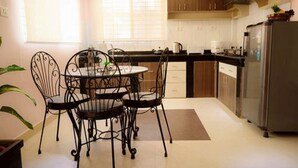Una cocina con una mesa redonda de comedor, cuatro sillas, un refrigerador y armarios de madera.
