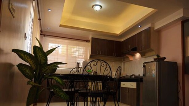 Una cocina con una mesa de comedor, sillas, un refrigerador y una planta en maceta.