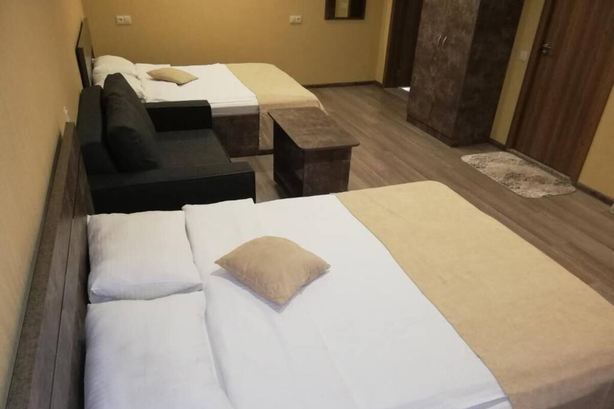 A hotel room with two beds, a sofa, and a small table.