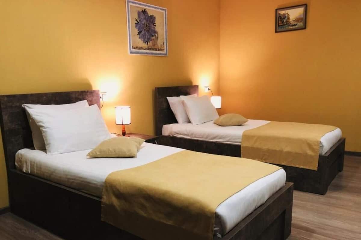 Two single beds with wooden headboards, white bedding, and a yellow accent on the foot of each bed.