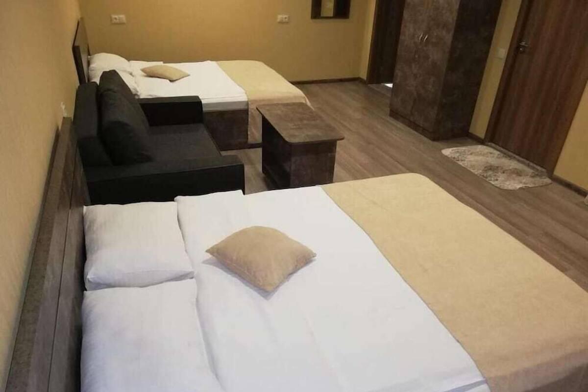 A hotel room with two beds, a sofa, a small table, and a wardrobe.