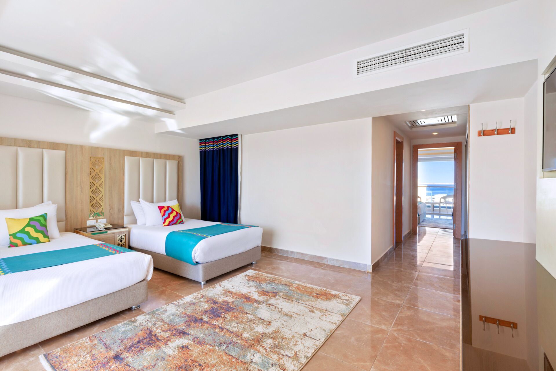 Habitación de hotel con dos camas, un ventanal grande y vista al mar.