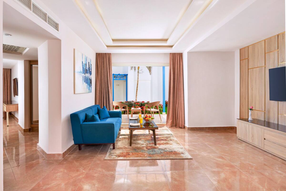 Een moderne woonkamer met een blauwe bank, een bijzettafeltje en uitzicht op het groen.