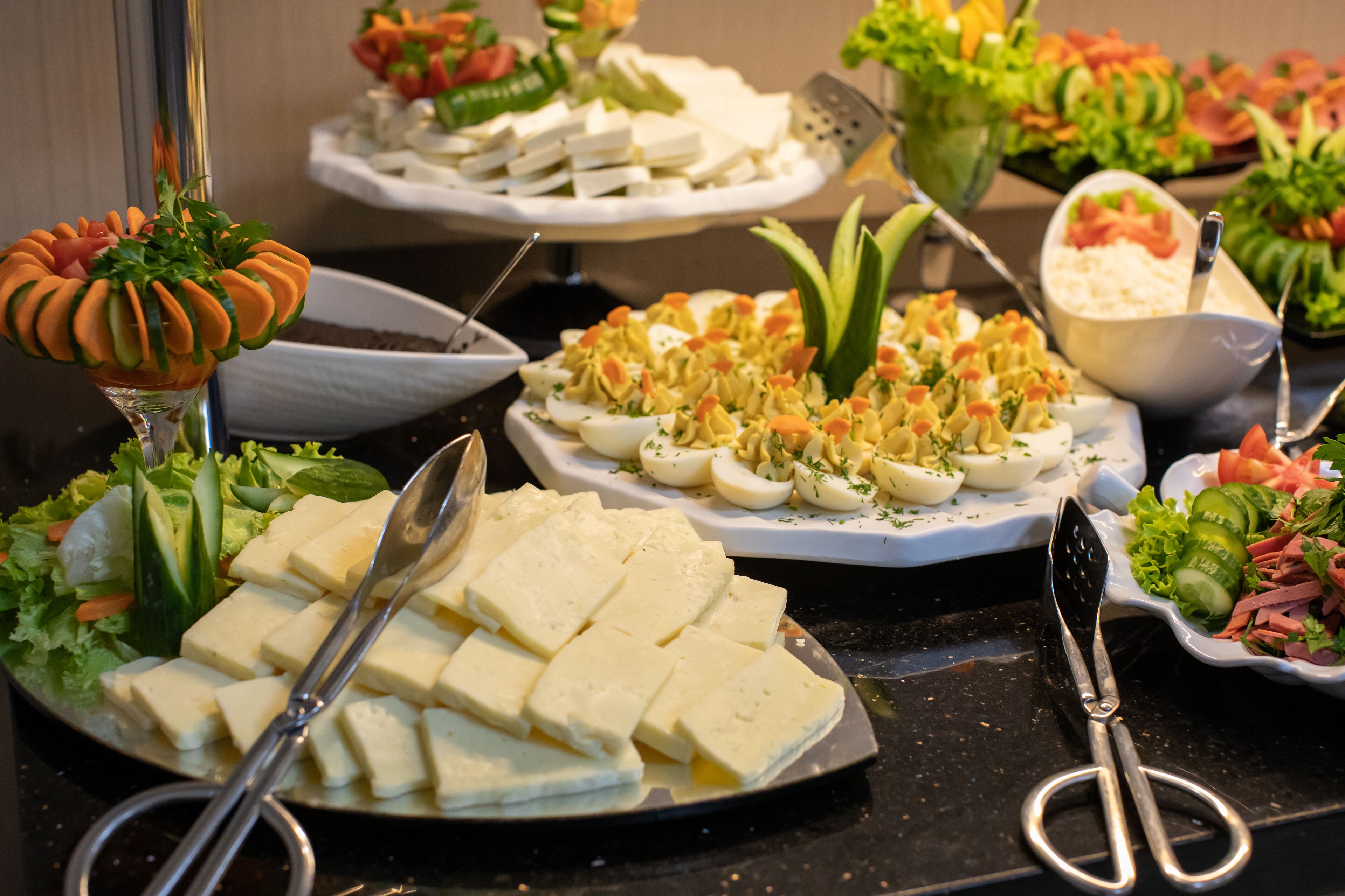 A buffet with various dishes including sliced cheese, eggs, and salads.