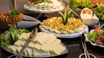 A buffet with various dishes including sliced cheese, eggs, and salads.