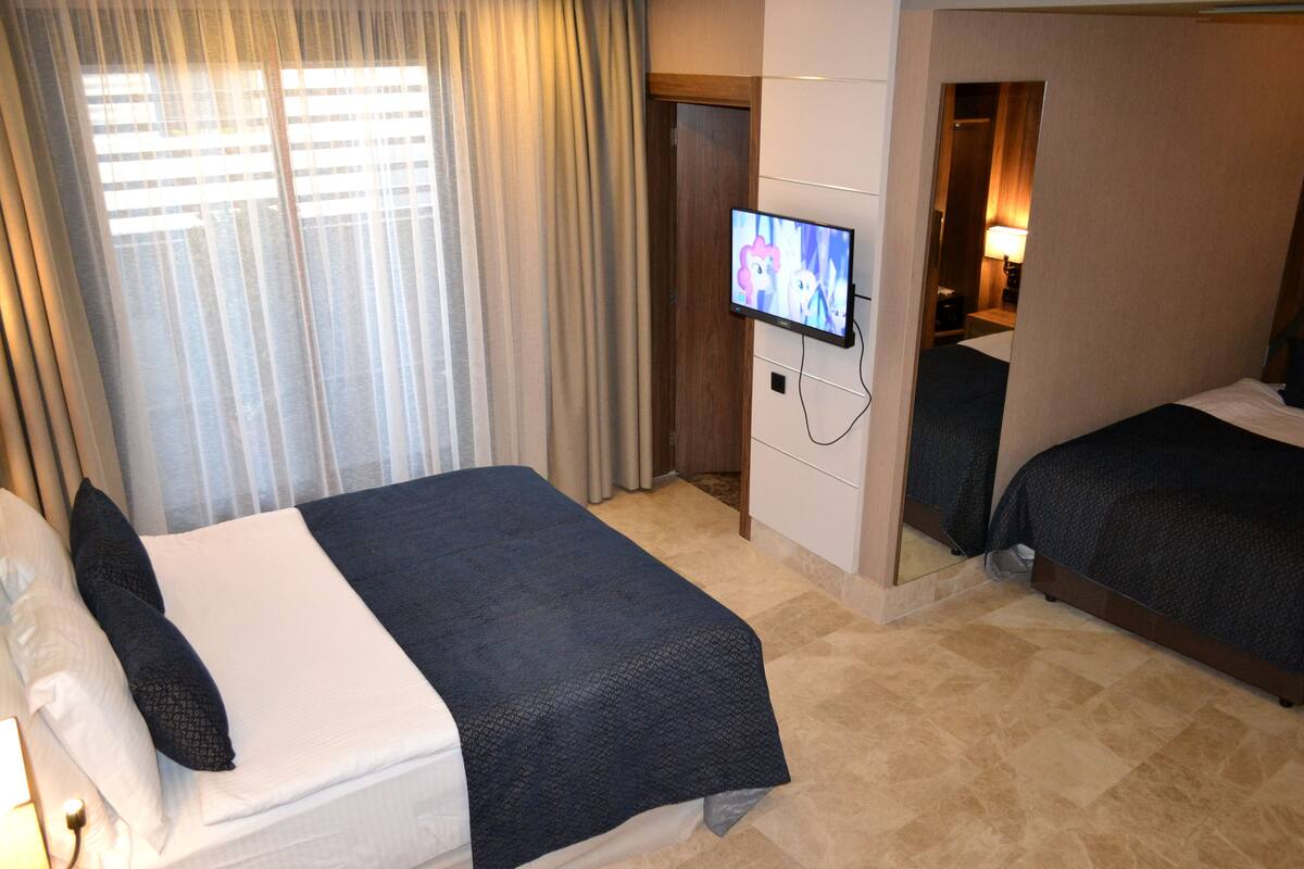 A hotel room with two beds, a TV, and a mirror.