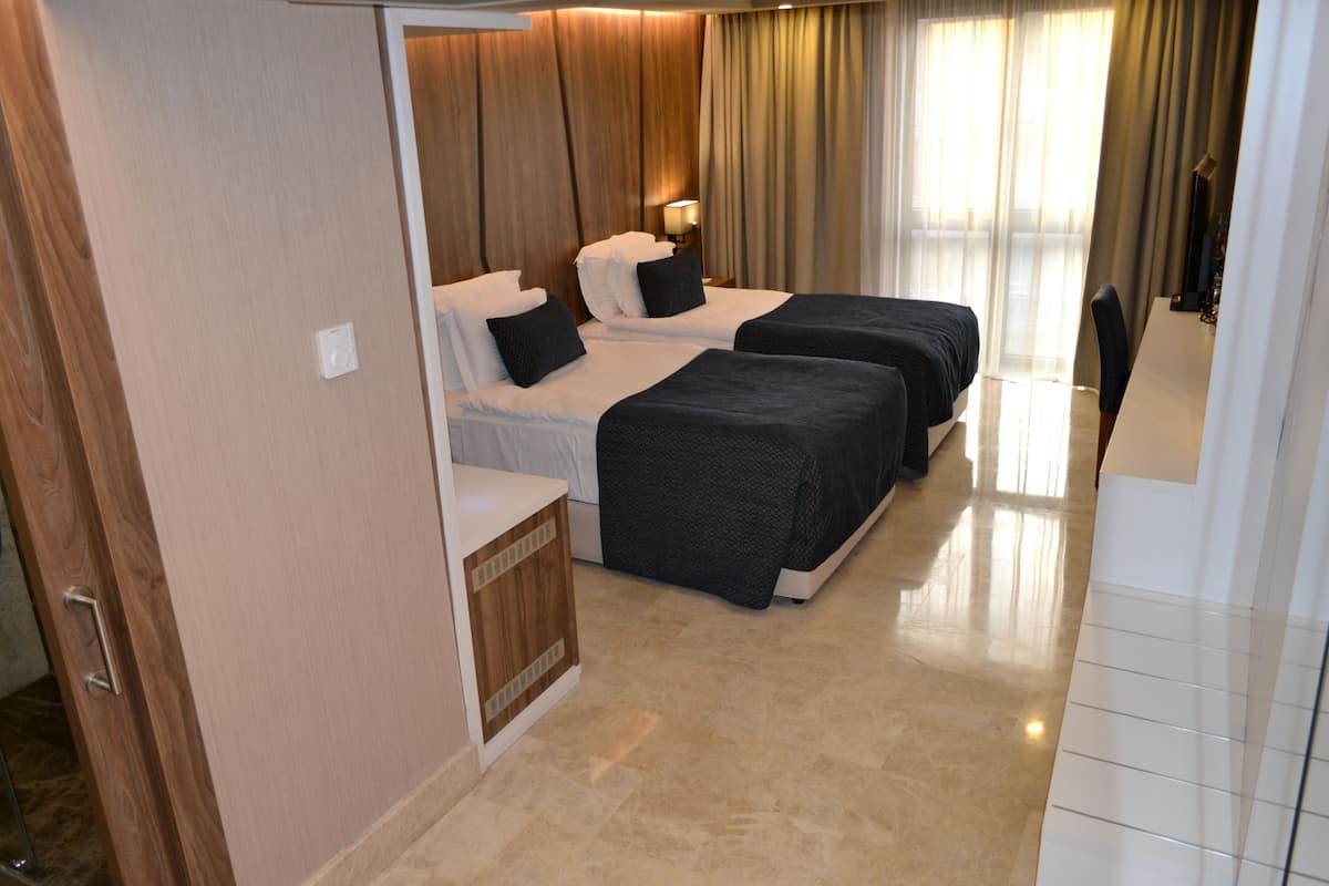 A hotel room with two beds, a desk, and a chair.