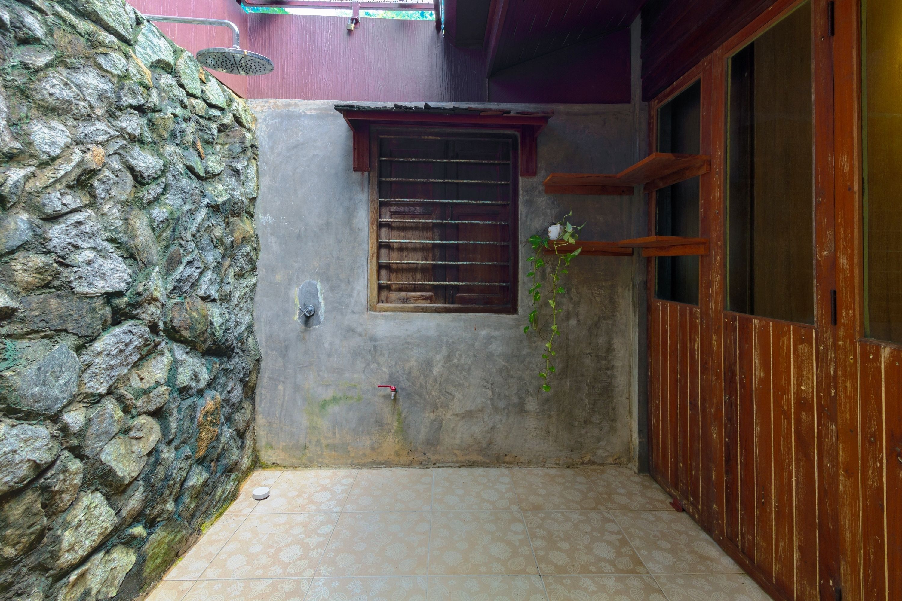 Un estrecho pasillo con una pared de piedra en un lado, una puerta de madera en el otro y una ventana con barrotes.