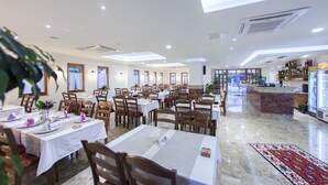 Un restaurante amplio con varias mesas y sillas, una zona de bar y vistas al exterior.