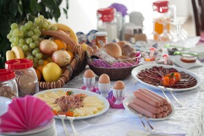 A table with various food items including fruits, cheeses, and meats, suggesting a buffet or communal meal setting.