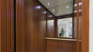 Una habitación con paneles de madera, un espejo que refleja un pasillo y una planta.
