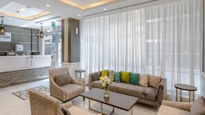 Un vestíbul d'hotel modern amb una recepció, zona de seients i grans finestres.