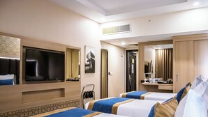Habitació d'hotel amb dos llits, un televisor, un mirall i un armari.