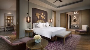 Une chambre d’hôtel moderne équipée d’un grand lit, d’un bureau, d’une chaise, d’une table ronde et d’un ventilateur de plafond.