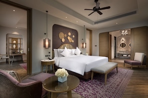Une chambre d’hôtel moderne équipée d’un grand lit, d’un bureau, d’une chaise, d’une table ronde et d’un ventilateur de plafond.