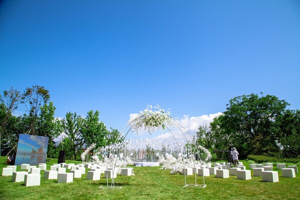 A cemetery with white headstones and a floral archway.