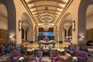A spacious lobby with a high ceiling, a central chandelier, and seating areas with tables and chairs. - Crowne Plaza Qingdao Oriental Movie Metropolis by IHG (Qingdao)