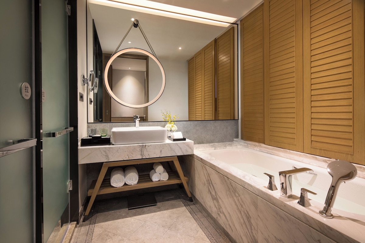 Une salle de bain moderne avec un lavabo en marbre, une baignoire sur pieds et un lambris en bois.