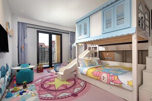 Une chambre d’enfant avec des lits superposés, un espace de jeux et une grande fenêtre.