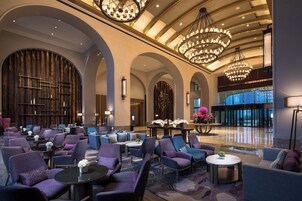 A spacious lobby with multiple seating areas, large chandeliers, and a modern interior design.