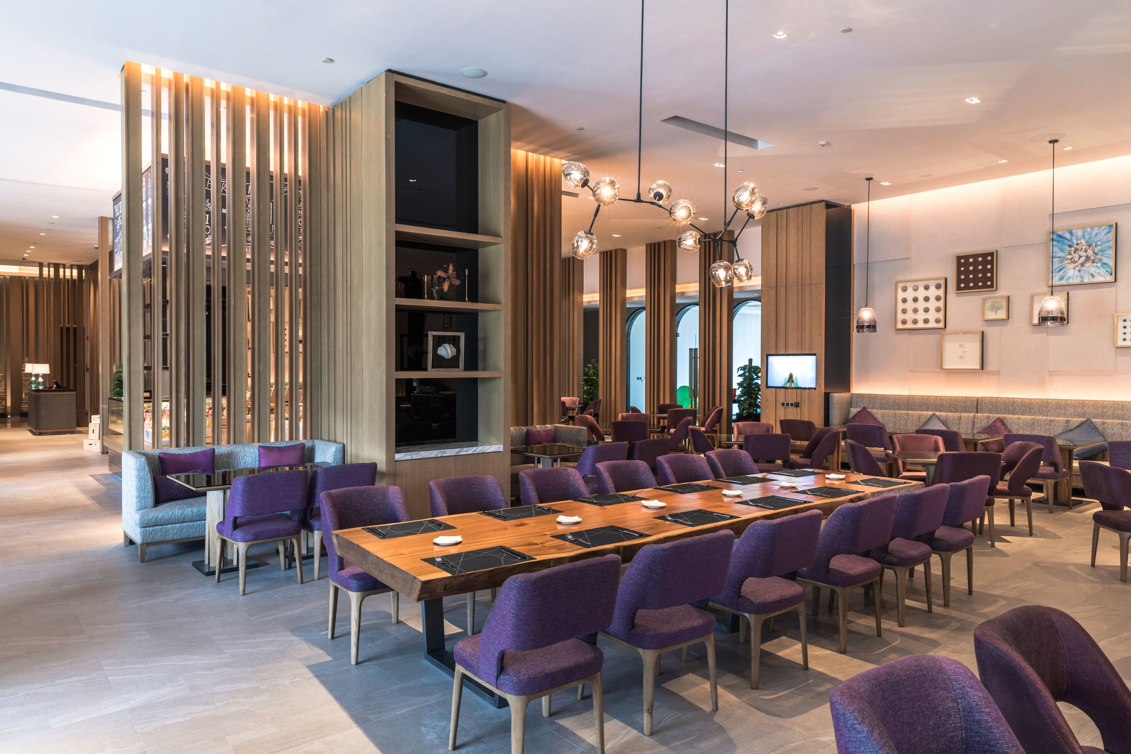 A spacious conference room with a long table, purple chairs, and a modern chandelier.