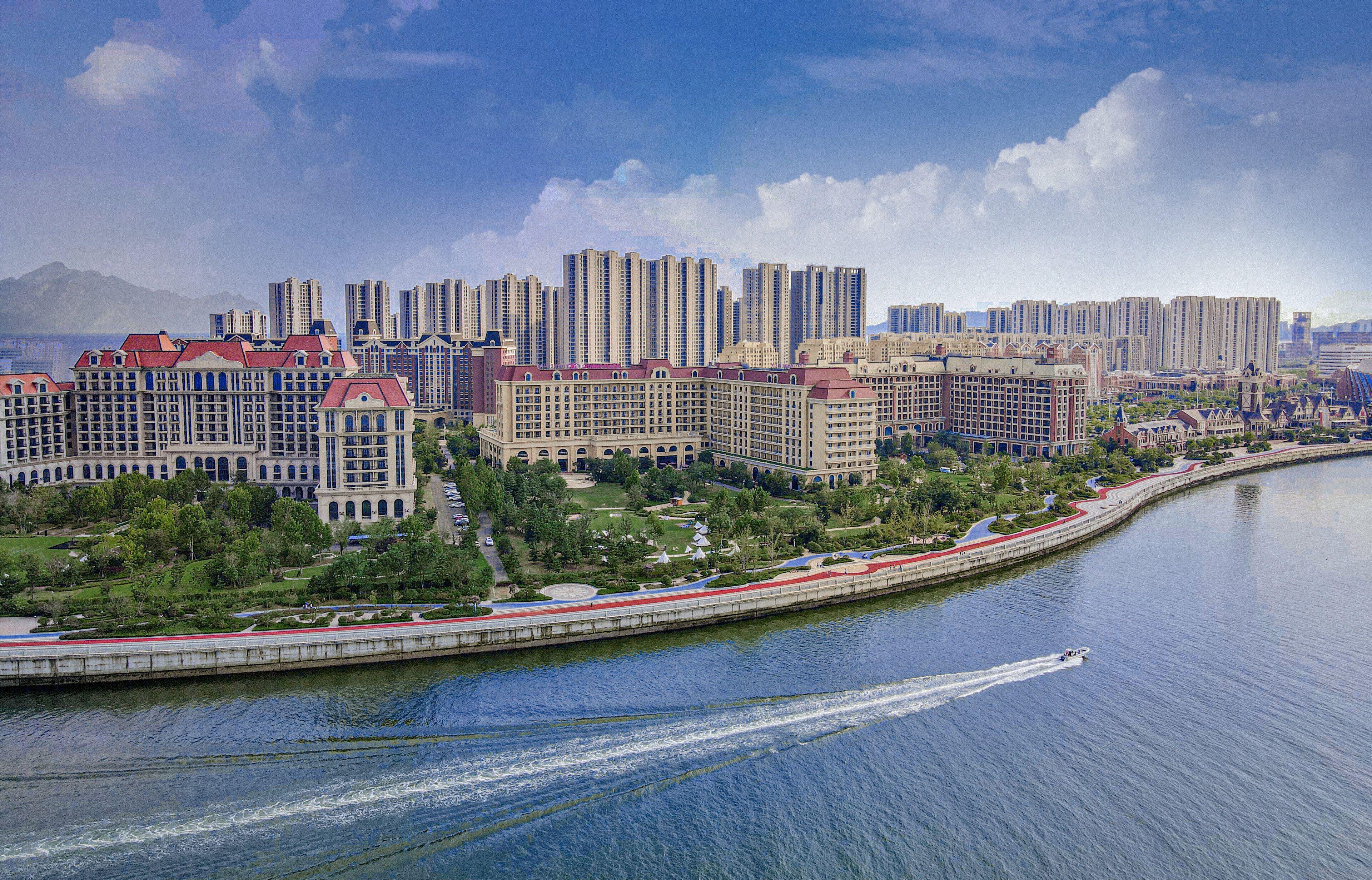 A waterfront hotel with multiple high-rise buildings, a river, and a bridge.