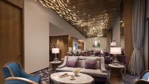 A hotel lobby with a modern design, featuring a central seating area with sofas and armchairs, a round marble coffee table, and ambient lighting. - Crowne Plaza Qingdao Oriental Movie Metropolis by IHG (Qingdao)