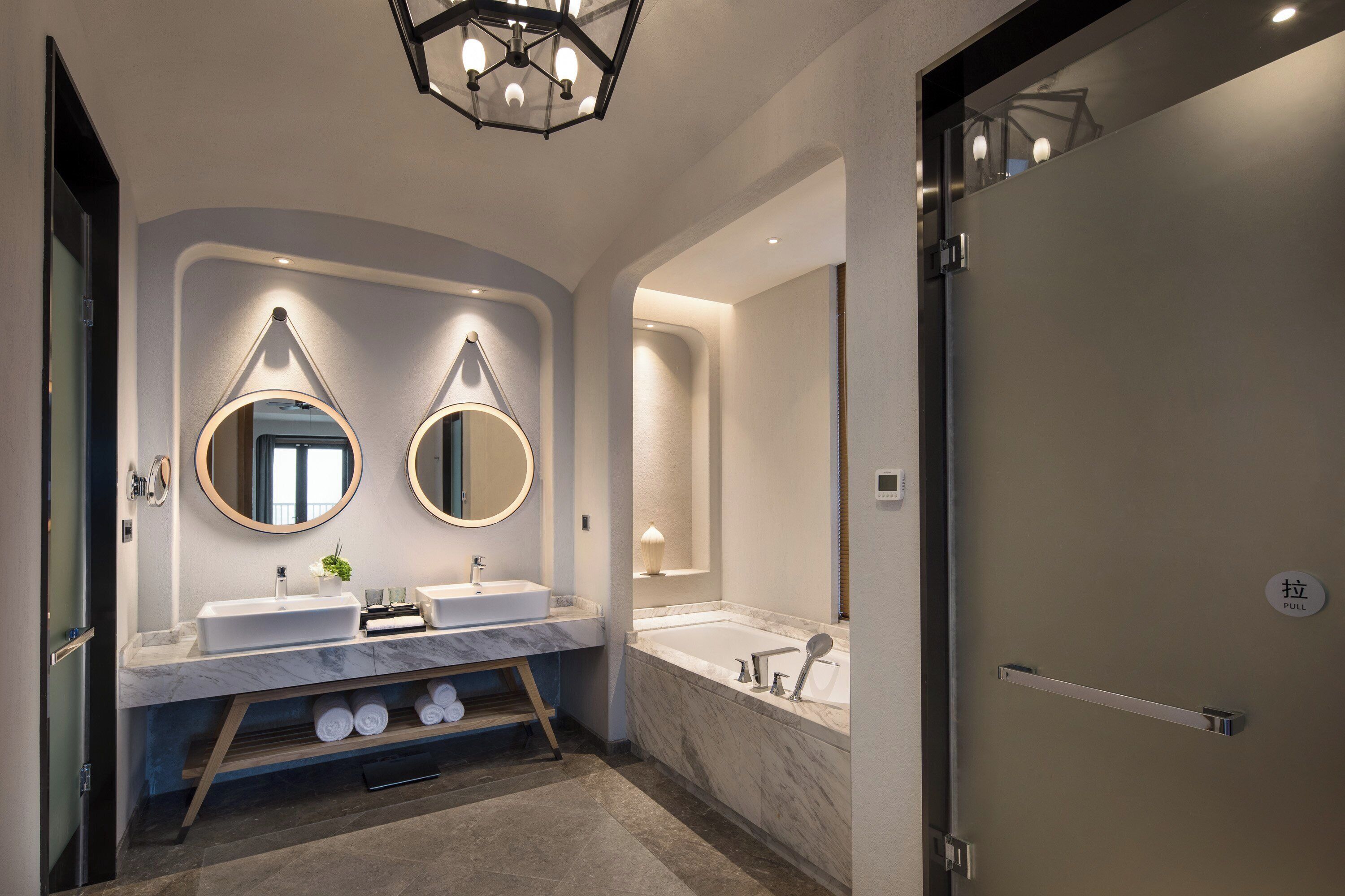 A modern bathroom with two sinks, a bathtub, and a vanity with a mirror.