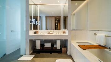 Un baño moderno con un espejo grande, lavamanos dobles, una bañera y un perchero para toallas.