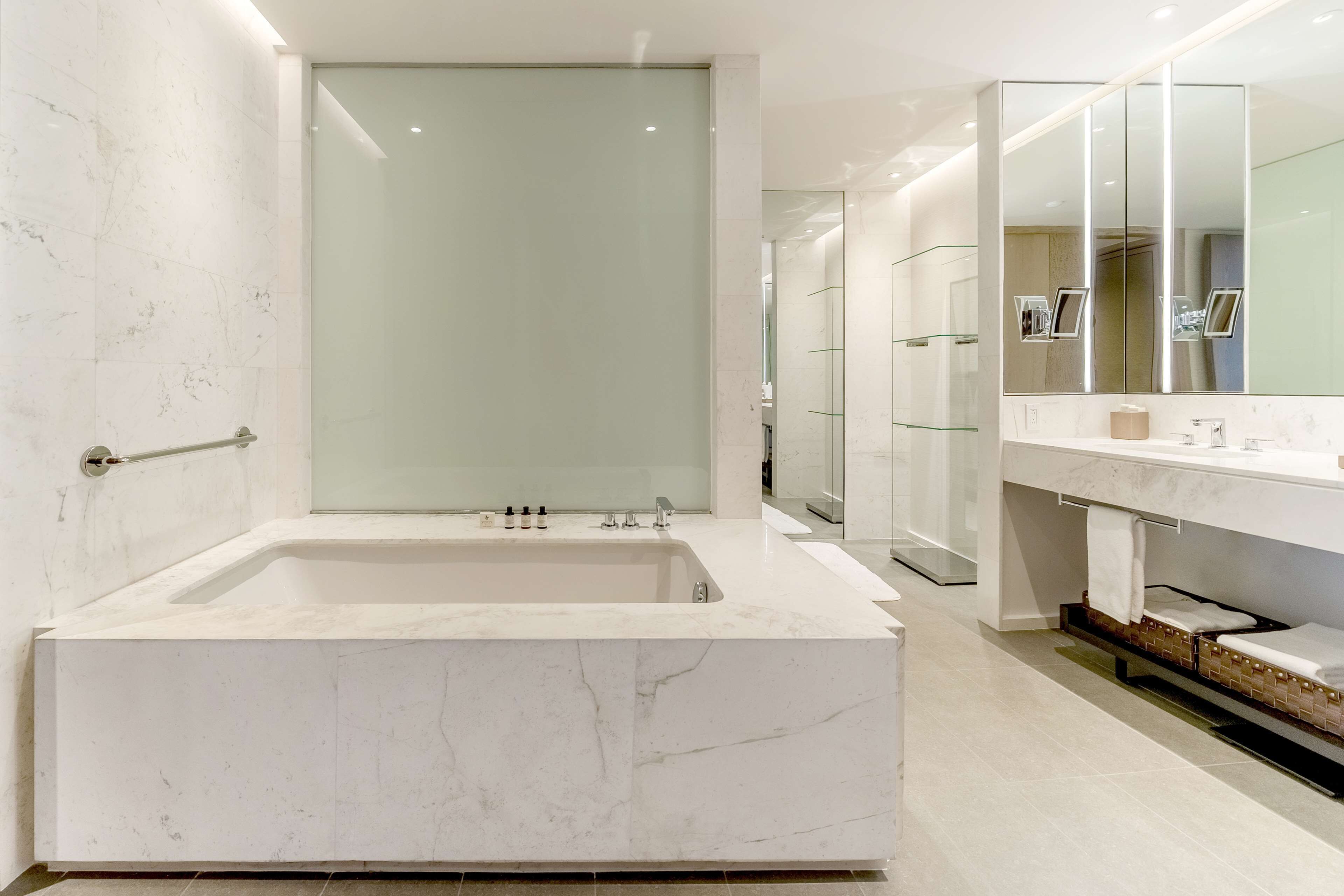 A modern bathroom with a large bathtub, a glass shower enclosure, and a large mirror above the sink.