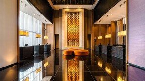 Eine moderne Hotelhalle mit spiegelndem Boden, einer Rezeption und einer Wand mit Musterung.