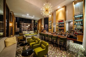A bar area with multiple seating options, a bar counter, and shelves stocked with bottles.