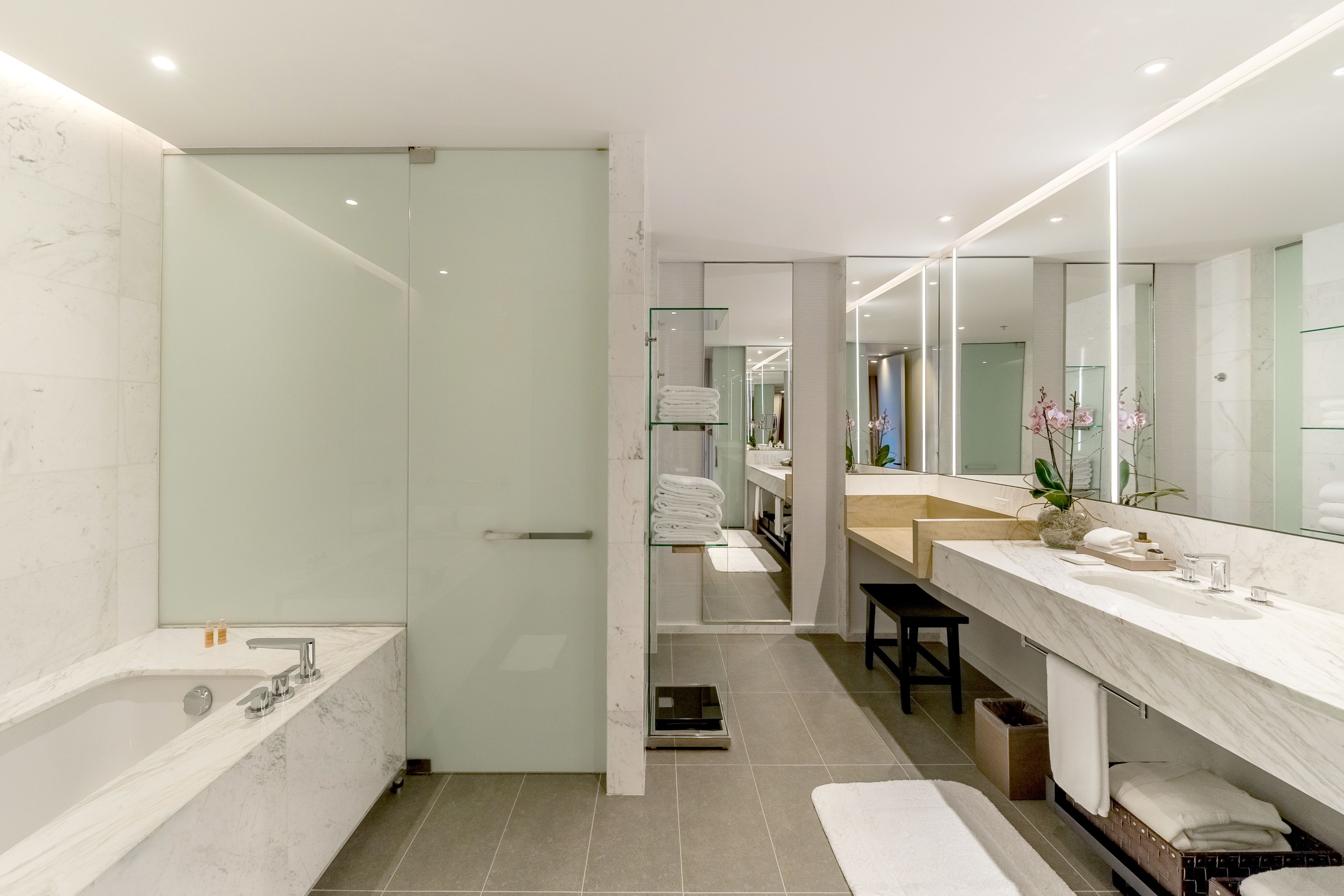 Un baño moderno con una bañera grande, cabina de ducha de vidrio y tocador con espejo.