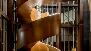 Ein modernes Interieur mit einer Wendeltreppe, großen Fenstern und einer außergewöhnlichen Leuchte.