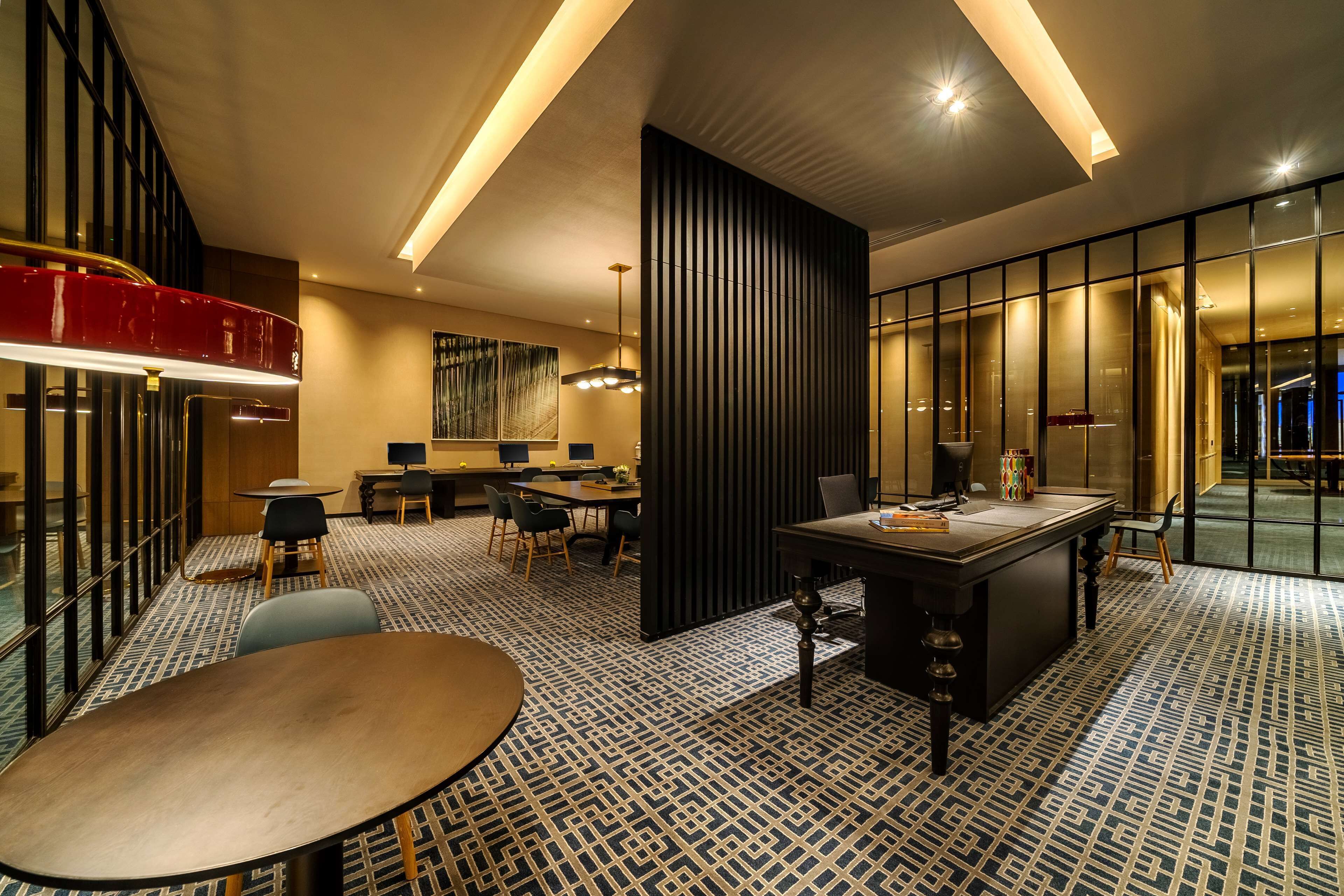Una hall d'albergo moderna con una grande reception, un'area salotto e un pavimento decorato.