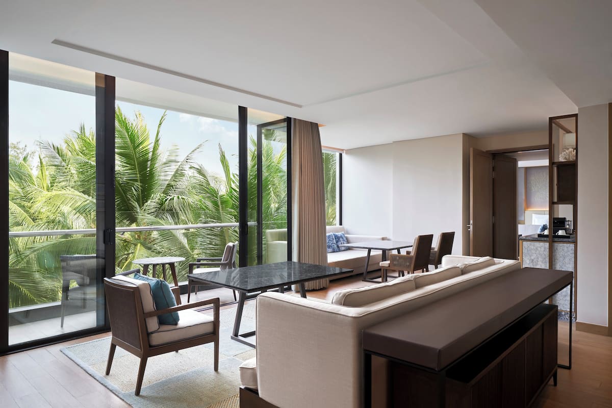 Un salon moderne doté d’une grande porte vitrée donnant sur un balcon, d’un canapé, d’une table à manger et d’un coin cuisine.