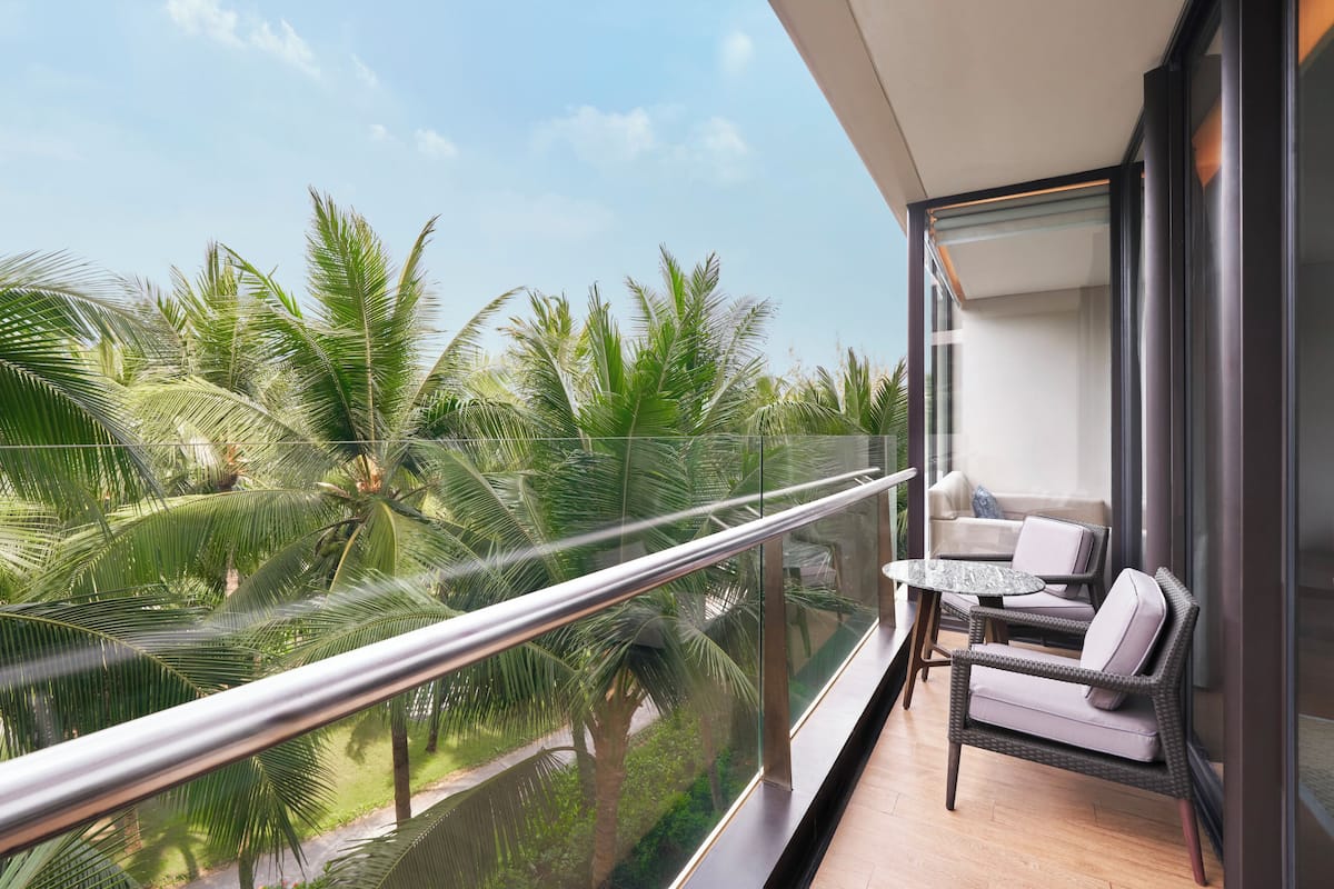 A balcony with a glass railing, a wicker sofa, and a small table.