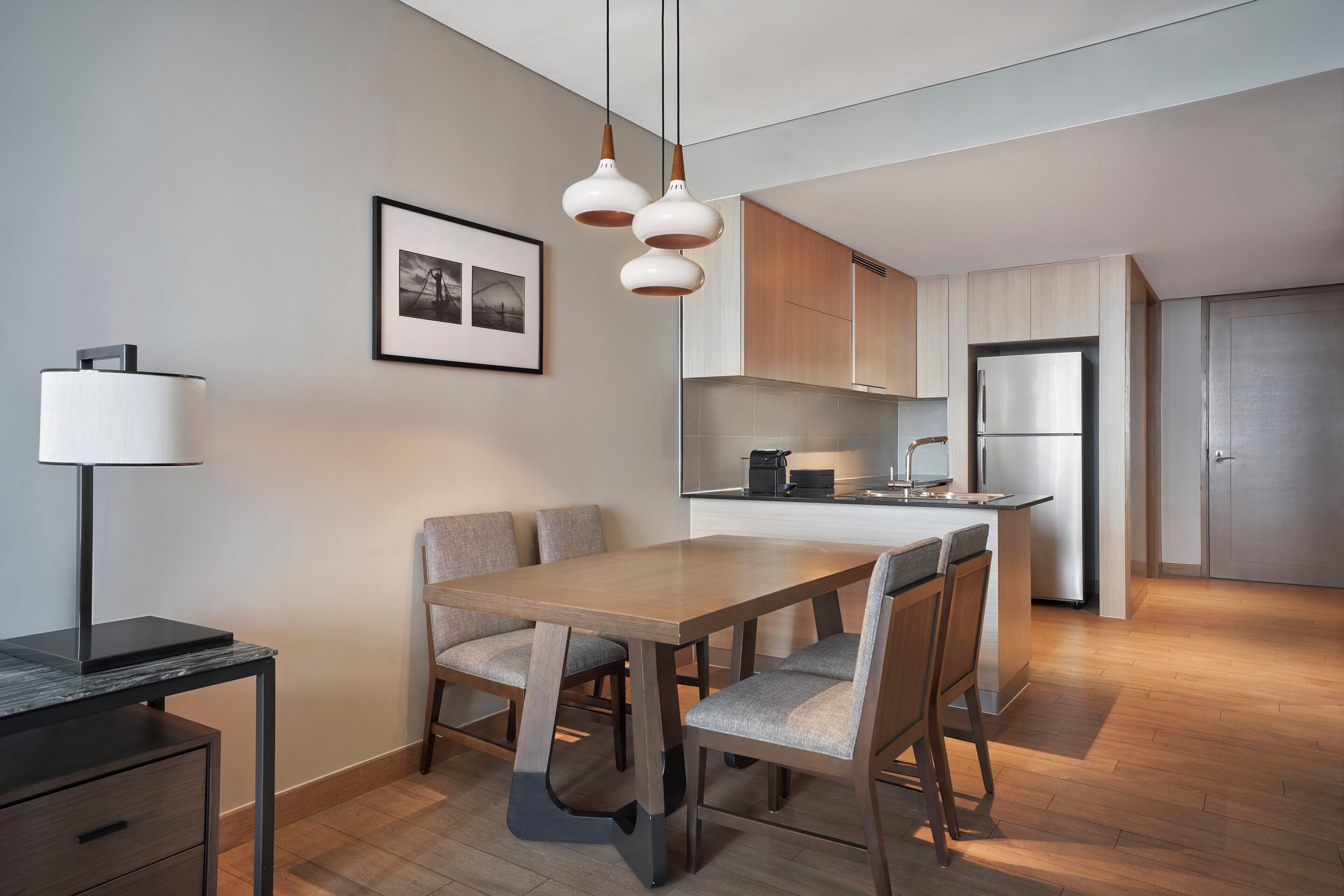 A modern kitchen with wooden cabinets, a built-in oven, and a stainless steel refrigerator.